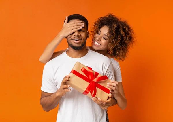 Beautiful girl covering her boyfriend eyes with present — Stock Photo, Image