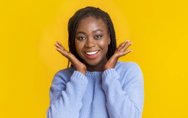 Neşeli Afrikalı Amerikalı kız elleriyle yanaklarına dokunuyor.