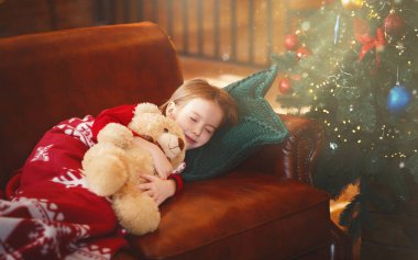 Parlayan Xmas ağacının yanında uyuyan küçük kız