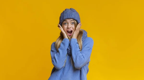 Удивительная девушка в зимней шляпе трогает ладонями свои щеки — стоковое фото