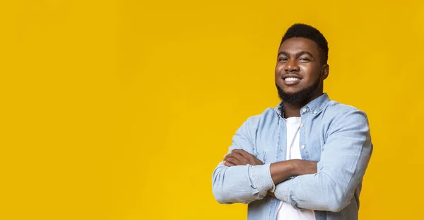 Attractive black guy with folded arms over yellow background — Stock Photo, Image