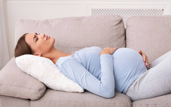 Pregnant Lady Suffering From Abdominal Pain Lying On Sofa Indoor