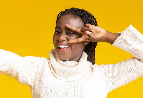 Carefree black girl taking selfie, covering eye with fingers — Stock Photo, Image