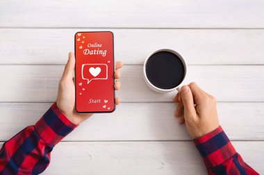 Tanımlanamayan adam akıllı telefonda flört uygulaması kullanıyor ve kahve içiyor.