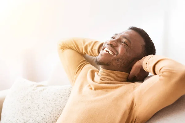 Mann sitzt zu Hause auf Sofa und hält die Hände hinter dem Kopf — Stockfoto