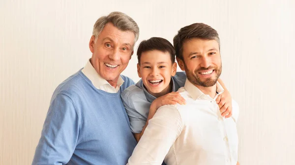 Usmívající se chlapec, otec a dědeček objímání stojící na bílém pozadí — Stock fotografie