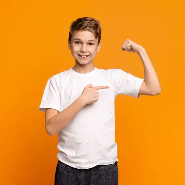 Leende tonårspojke demonstrerar sina biceps på kameran — Stockfoto