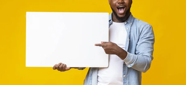 Afričan drží bílou reklamní tabuli a ukazuje na ni — Stock fotografie