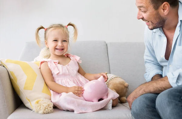 Fille heureuse assise avec son père, tenant une tirelire — Photo