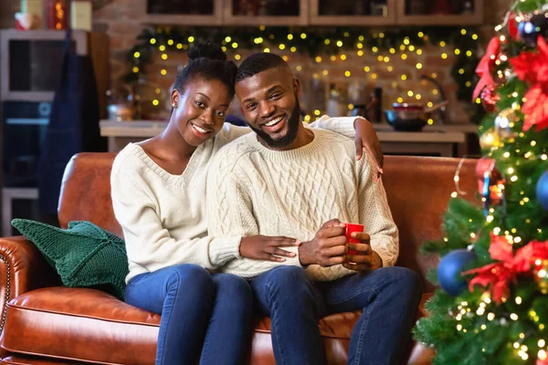 Африканська пара насолоджується різдвяним вечором, обіймаючи і посміхаючись у фотоапараті — стокове фото