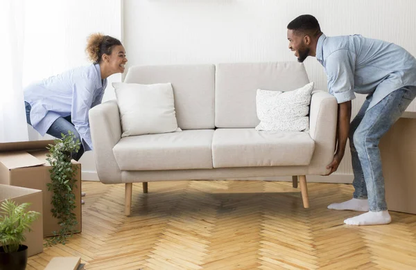 Весёлые афро-супруги Размещение дивана Мебель пустая комната в новом доме — стоковое фото