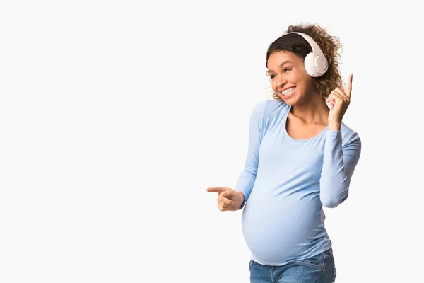 Счастливая беременная женщина слушает музыку и танцует — стоковое фото