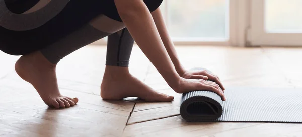 Nahaufnahme einer sportlichen Frau, die Yogamatte rollt — Stockfoto