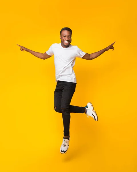 Fröhlicher schwarzer Kerl springt mit Spaß über gelben Hintergrund — Stockfoto