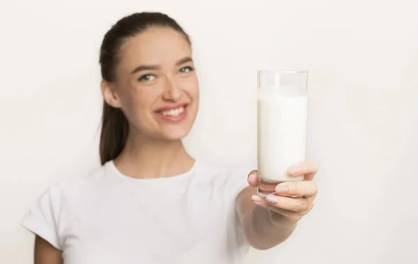 Girl Offering Glass Of Milk Standing Over White Studio Background — ストック写真