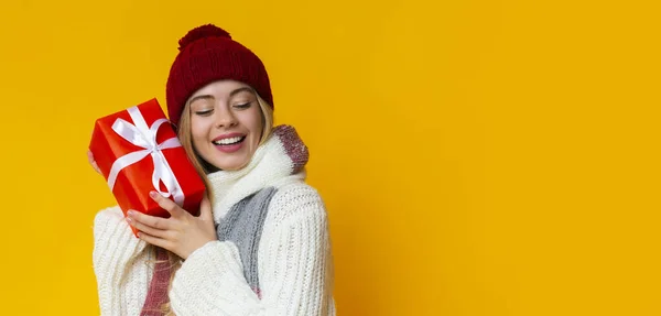 Soñando invierno chica hodling regalo de Navidad sobre fondo amarillo —  Fotos de Stock