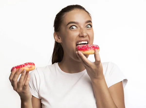 Hambrienta chica comiendo donas de pie sobre fondo blanco — Foto de Stock