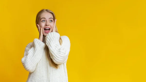 Verbijsterd blond meisje aanraken van haar wangen, kijken naar kopieerruimte — Stockfoto