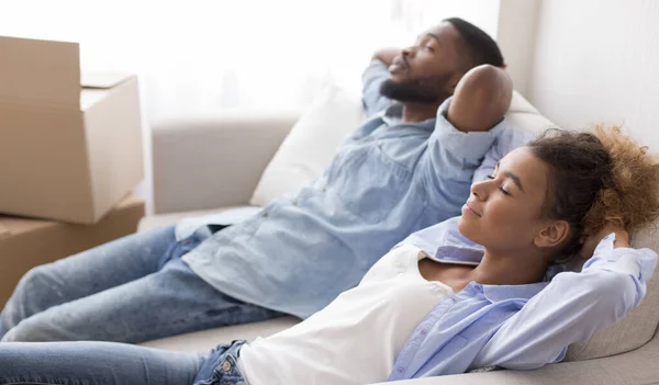 Μαύροι σύζυγοι αναπαύονται κρατώντας τα χέρια πίσω από το κεφάλι κάθεται στον καναπέ — Φωτογραφία Αρχείου