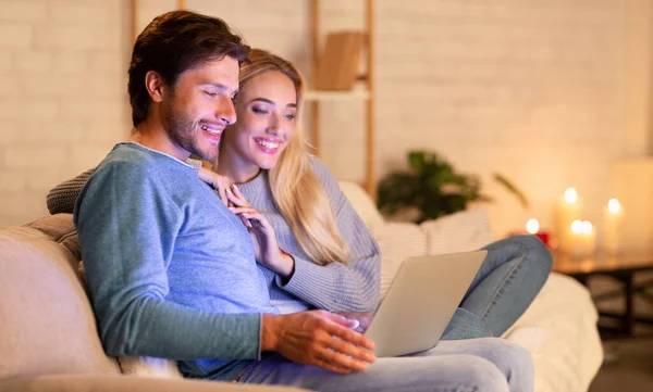 Pareja viendo la película en el ordenador portátil sentado en el sofá en casa —  Fotos de Stock