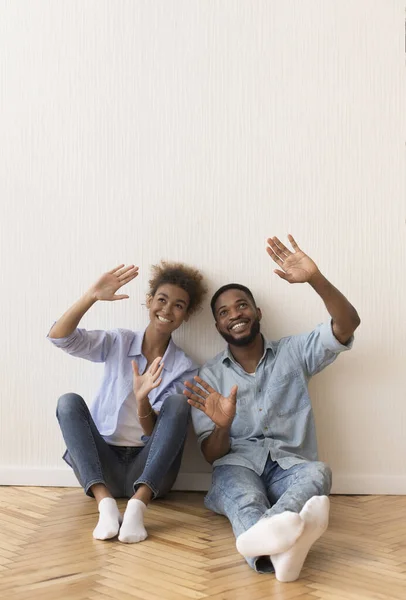Улыбающиеся афро-пара планирование интерьера сидит на полу в помещении — стоковое фото