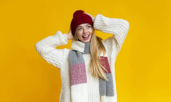 Garota excitada de chapéu de malha olhando para o fundo amarelo — Fotografia de Stock