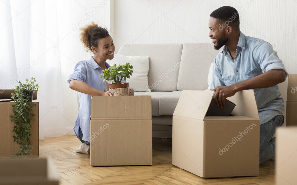 Happy Spouses Packing Stuff In Boxes Sitting On Floor Indoor