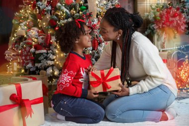 Mutlu afro anne ve kızlar Noel ağacının yanında hediye kutusuyla
