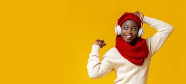 Kablosuz kulaklıklı heyecanlı afro kız müzik dinliyor, dans ediyor.