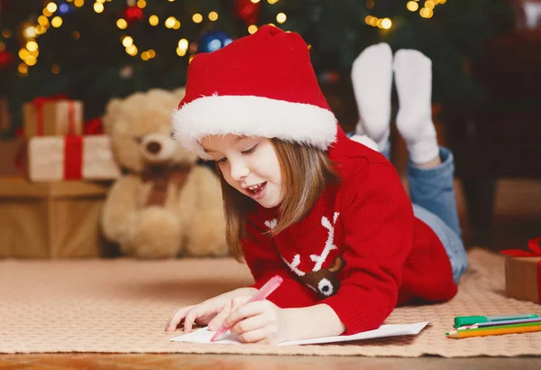 Niña soñadora escribiendo carta a Santa bajo el árbol de Navidad —  Fotos de Stock