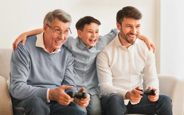 Hombre familia de tres jugando videojuegos sentado en sofá interior — Foto de Stock