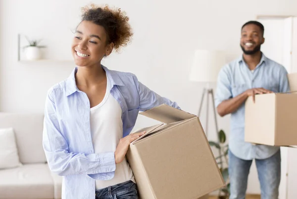 Gelukkig zwart echtgenoten dragen verpakt dozen in nieuwe appartement — Stockfoto