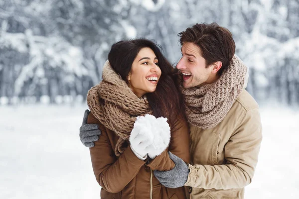 Conjoints joyeux tenant la neige et étreignant debout dans la forêt d'hiver — Photo