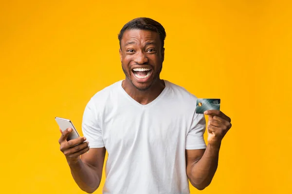 Happy Man Holding Smartphone And Credit Card Standing, Studio Shot — Stock Photo, Image