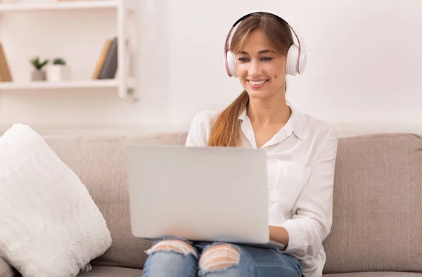 Mädchen mit Laptop hört Podcast auf Couch im Haus — Stockfoto