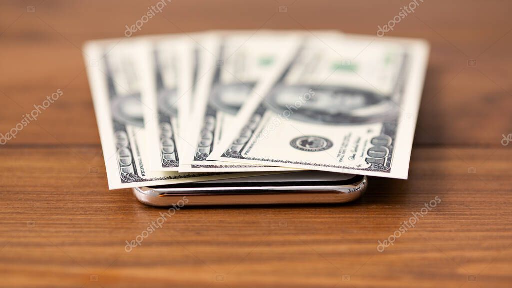 Bunch of dollars flat lying on modern smartphone