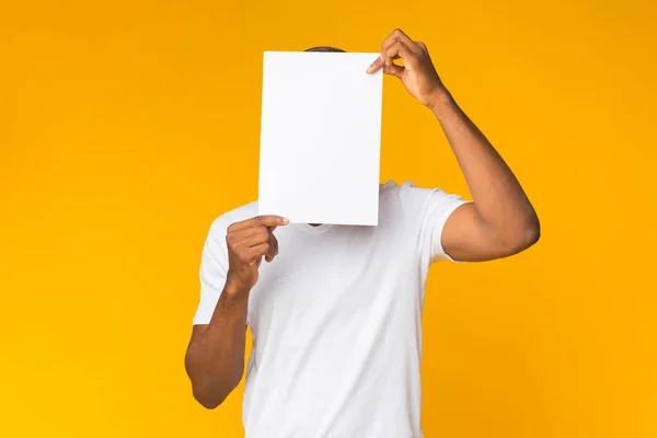 Man Standing Covering Face With White Paper, Studio Shot