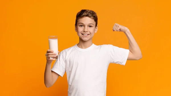 自信而强壮的青少年，一边喝牛奶，一边展示他的二头肌 — 图库照片