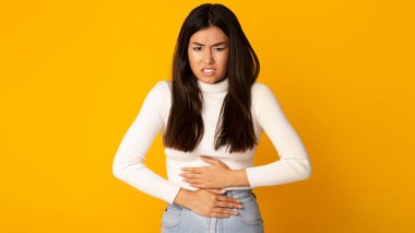 Asian girl with stomachache having food poisoning clipart