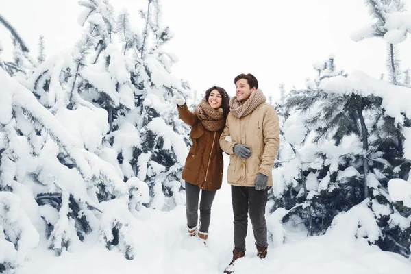 Mädchen zeigt mit Finger auf Freund, der im Winterwald steht — Stockfoto