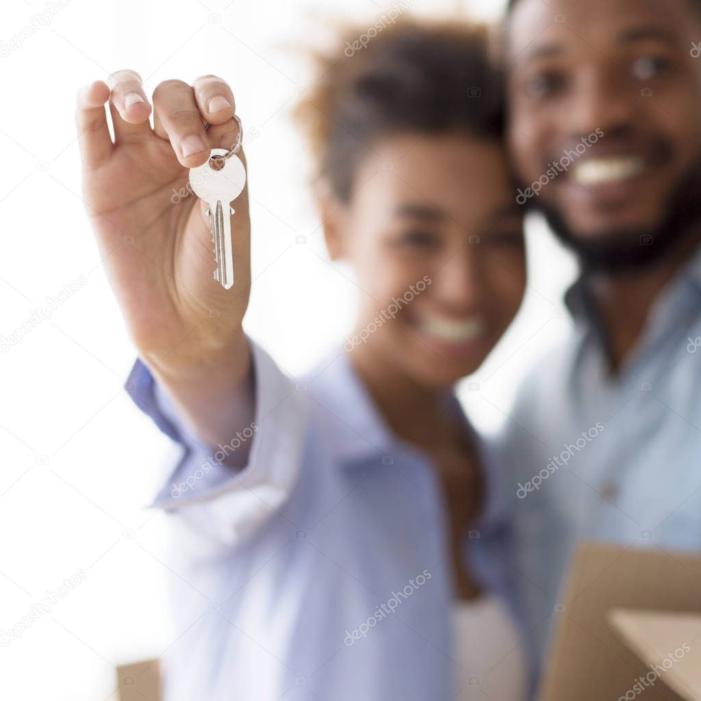 African American Spouses Hugging Showing Keys Standing In New Home