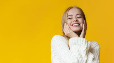 Neşeli genç bayan yanaklarına dokunuyor ve gülümsüyor