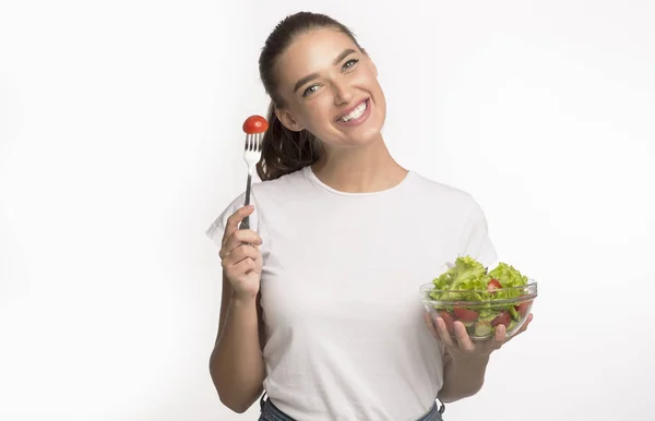 Kvinna äter färsk grönsakssallad stående i studio, isolerad — Stockfoto