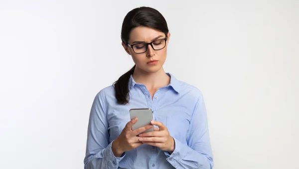 Serieuze zakenvrouw met behulp van Smartphone SMS Staande in Studio — Stockfoto
