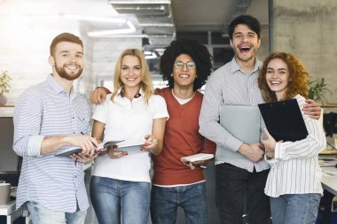 Ofiste kameraya gülümseyen bir grup genç profesyonel.