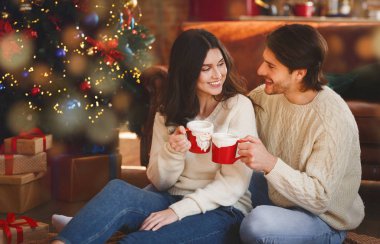 Neşeli adam ve kadın Noel ağacında içki içiyorlar.