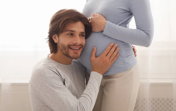 Loving husband listening to his pregnant wifes belly — Stock Photo, Image