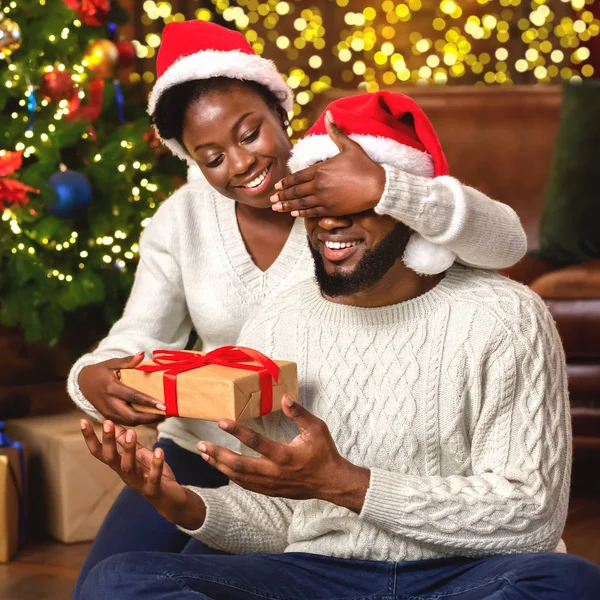 Sevgi dolu siyah kadın Noel hediyesiyle kocasını şaşırtıyor. — Stok fotoğraf