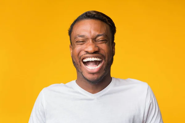 Портрет смеющегося чернокожего человека, стоящего на желтом фоне, студия — стоковое фото