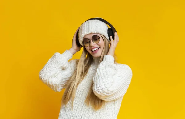 Blondýny zimní žena v slunečních brýlích a sluchátka poslech hudby — Stock fotografie